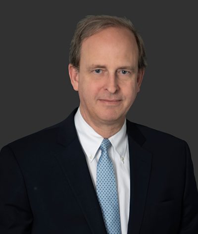 Keith Ausbrook in a suit and tie smiling for a professional headshot
