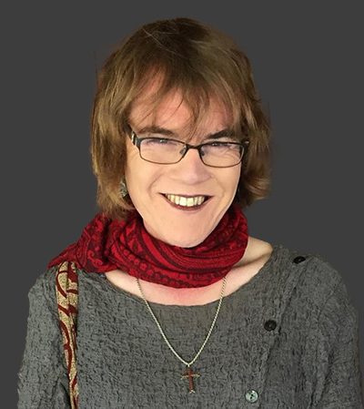 Michele French wearing glasses and a red scarf is smiling