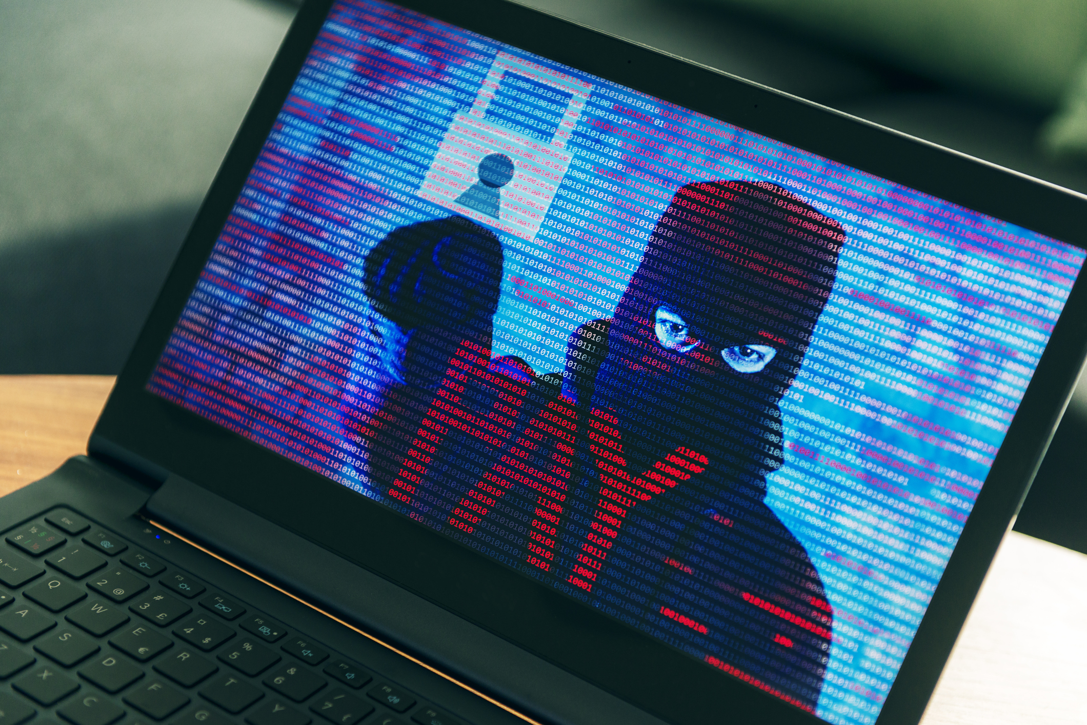 a laptop computer with a ransomware message with a man in a mask on the screen