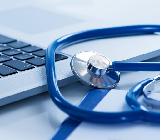 a stethoscope rests on top of a laptop keyboard