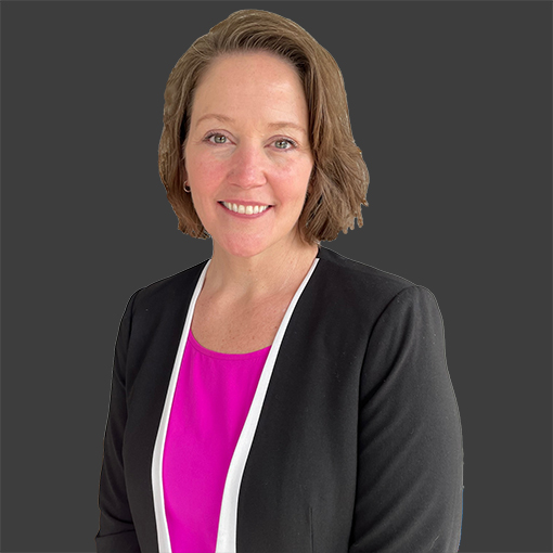 Jean Moore wearing a black jacket and a pink shirt is smiling for the camera smiling for the camera