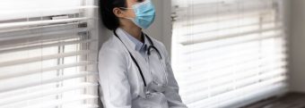 a doctor wearing a mask is leaning against a wall