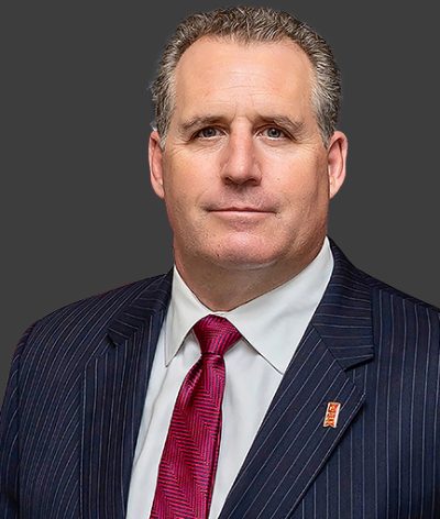 Robert Bell in a suit and tie in front of a gray background