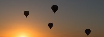 five hot air balloons are flying in the sky at sunset