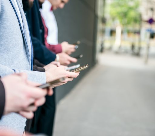 a group of young businessmen are standing next to each other looking at their cell phones