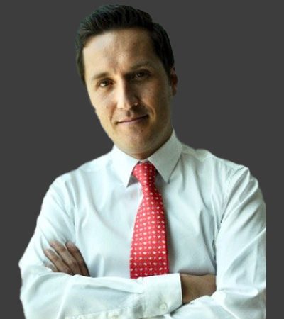 Leal in a white shirt and red tie is smiling for a professional photograph