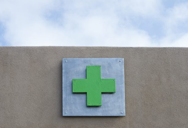 a green plus sign on a metal sign on a wall