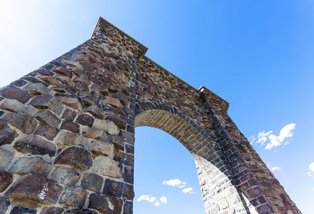 Roosevelt stone archway with a blue sky in the background at the north entrance of Yellowstone National Park in Gardiner, Montana.