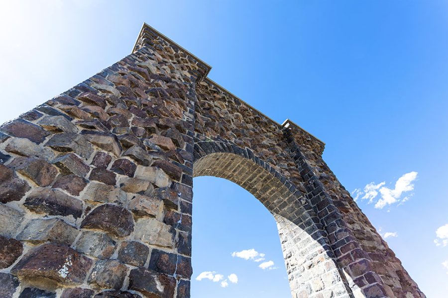 Roosevelt stone archway with a blue sky in the background at the north entrance of Yellowstone National Park in Gardiner, Montana.