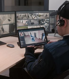 a security guard wearing headphones is sitting at a desk looking at video monitors