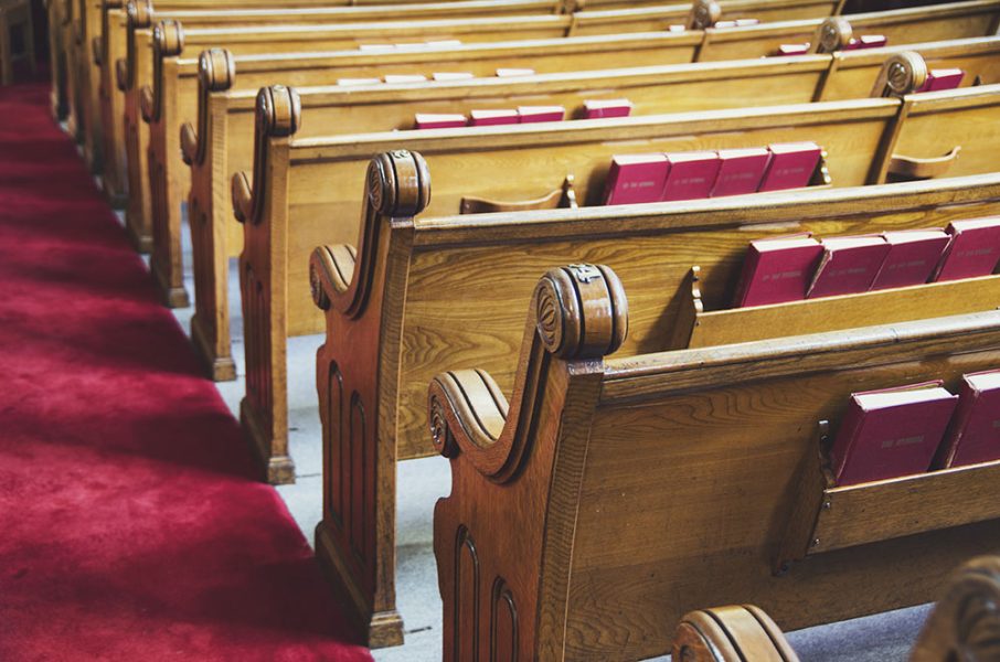 rows of wooden church pews with a red carpet