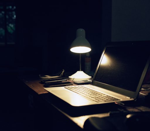 a laptop sits on a desk under a lamp