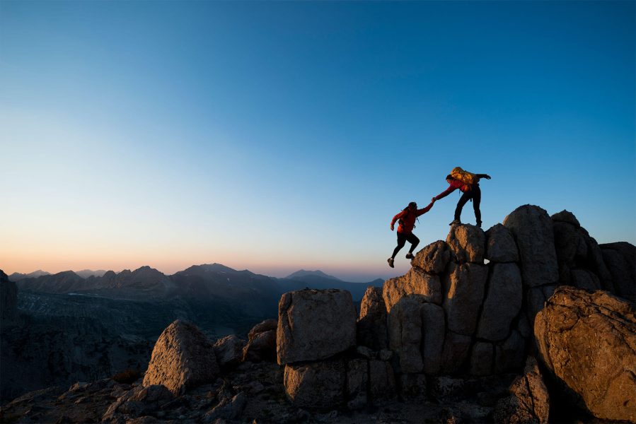 una persona que ayuda a otra a escalar una montaña