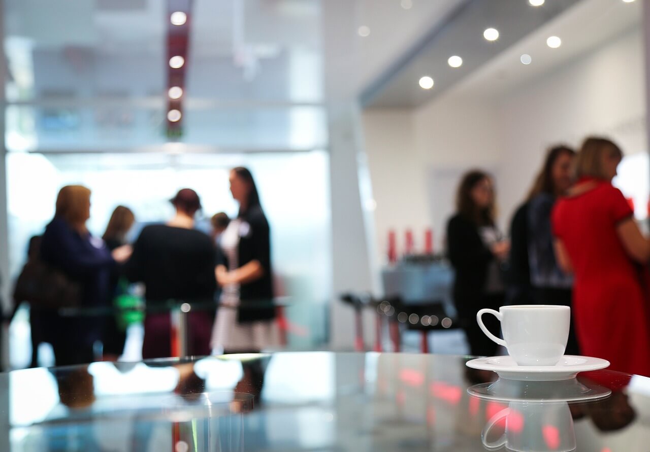 a coffee cup sits on a saucer in front of a group of people